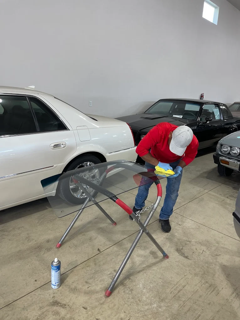 Technician prepping new windshield on glass stand before installation