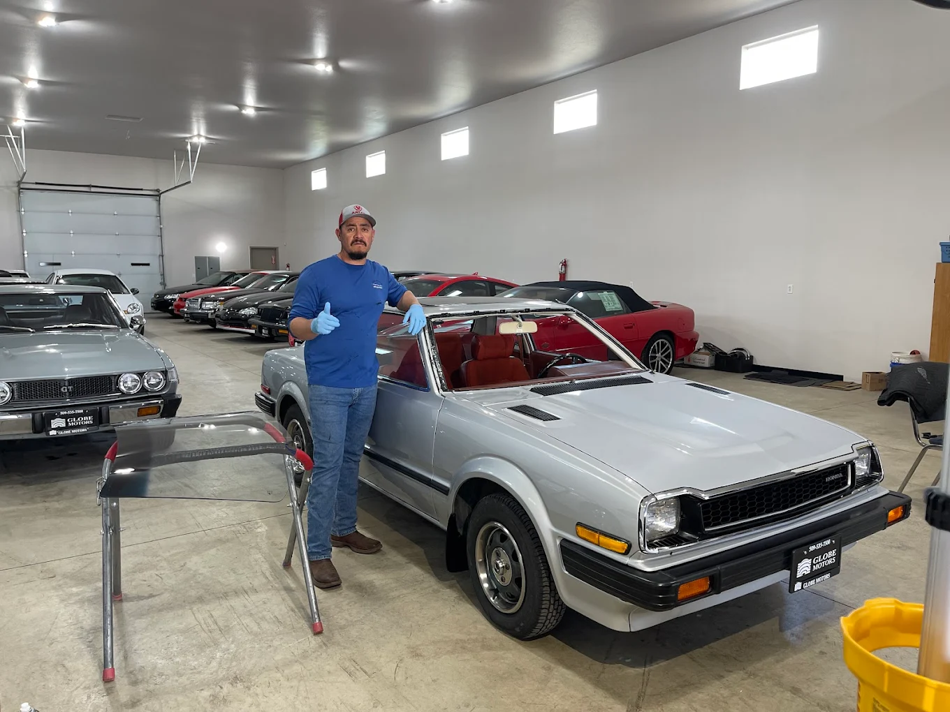 Technician with completed windshield work at collector garage